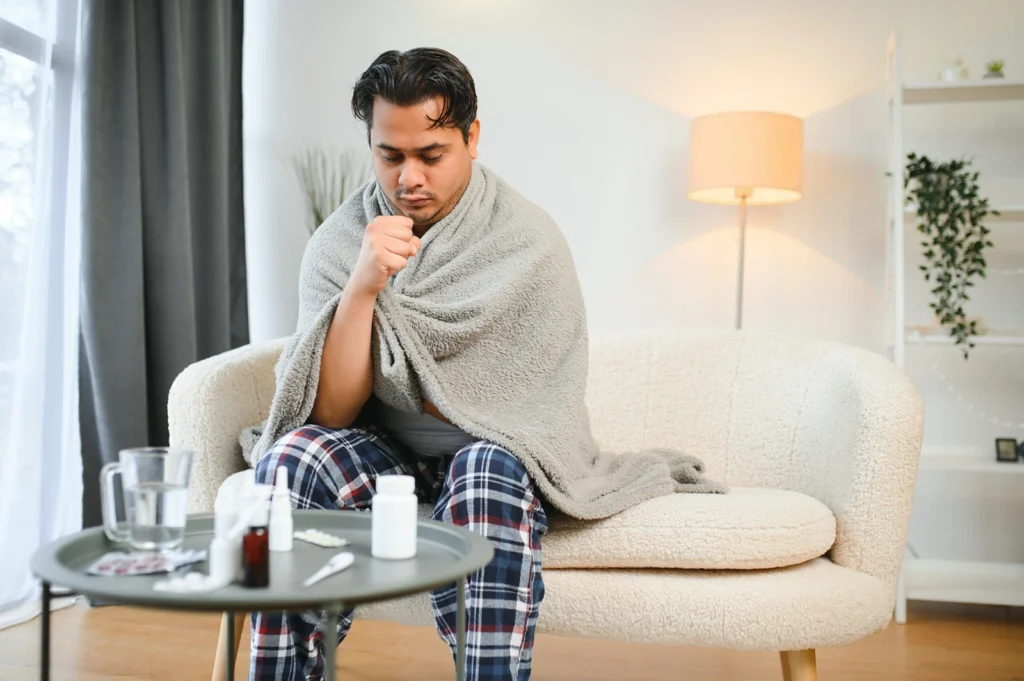 Man coughing under blanket on sofa at Belfast Private GP in Belfast