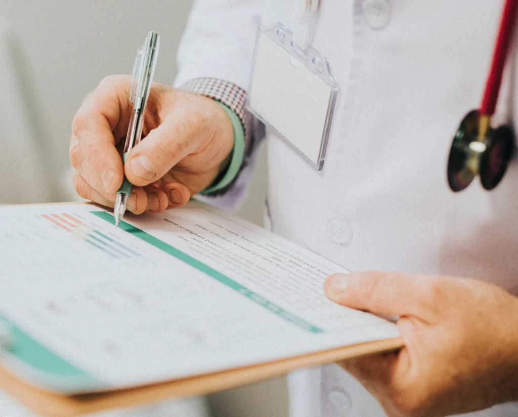 Doctor writing notes on patient chart at Belfast Private GP in Belfast