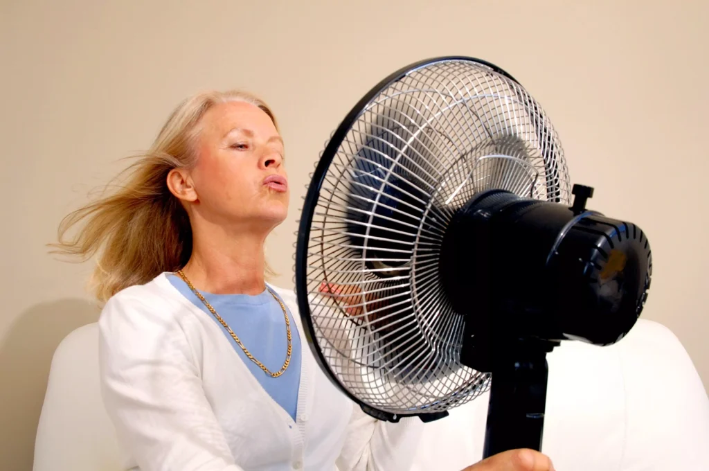 Woman cooling herself with electric fan at Belfast Private GP in Belfast