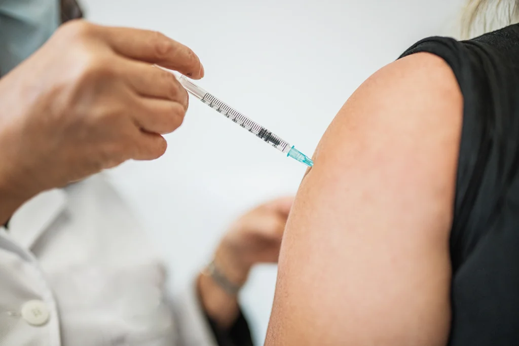 Doctor administering vaccine injection in patient's arm at Belfast Private GP in Belfast